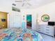 Bright bedroom with ceiling fan, ensuite bathroom, dresser with mirror and colorful floral comforter at 16604 Caribbean Breeze Way, Clermont, FL 34714