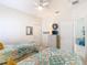Bright bedroom with ceiling fan, ensuite bathroom, and two twin beds with colorful floral comforters at 16604 Caribbean Breeze Way, Clermont, FL 34714