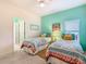Bright bedroom with ceiling fan, ensuite bathroom, and two twin beds with colorful floral comforters at 16604 Caribbean Breeze Way, Clermont, FL 34714