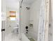 Clean bathroom featuring shower-tub combo, white tiled walls, and neutral shower curtain with grey marbled floors at 17409 Division St, Montverde, FL 34756