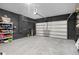 Spacious garage with modern black brick walls, concrete flooring, and a large white garage door at 2264 Emerald Springs Dr, Apopka, FL 32712