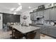 Stylish kitchen boasts gray cabinets, granite countertops, mosaic backsplash, an island with seating and a view of the dining area at 2264 Emerald Springs Dr, Apopka, FL 32712
