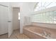 Bright bathroom features a large soaking tub with glass block window and natural light at 23 Old Sunbeam Dr, South Daytona, FL 32119