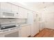 Efficient kitchen layout with white appliances, and hardwood floors, offering a convenient and functional space for cooking and cleaning at 23 Old Sunbeam Dr, South Daytona, FL 32119