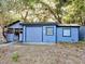 A detached, light blue garage sits in a yard surrounded by trees and foliage at 237 W Mcclendon St, Lady Lake, FL 32159