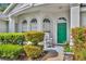 Inviting front porch features a rocking chair and a vibrant green door, complemented by lush shrubbery at 288 Englenook Dr, Debary, FL 32713