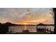 Panoramic view of the lake featuring a dock and gazebo at sunset, reflecting a golden glow on the tranquil water at 3108 Troy Dr, Orlando, FL 32806