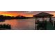 Lake view featuring a dock and gazebo at sunset, reflecting a golden glow on the tranquil water at 3108 Troy Dr, Orlando, FL 32806