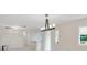 Open-concept living space with modern light fixture, white walls, and partial kitchen view at 3108 Troy Dr, Orlando, FL 32806