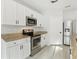 Close-up of the kitchen area features stainless steel appliances and sleek white cabinetry with granite countertops at 3443 Berkshire Woods Ter, Deltona, FL 32725
