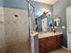 Bright bathroom featuring a shower with glass door, a vanity with drawers, and neutral tile at 3579 Maple Ridge Loop, Kissimmee, FL 34741