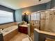 Bathroom featuring a soaking tub, walk-in shower, and tiled surround at 3579 Maple Ridge Loop, Kissimmee, FL 34741