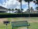 A green bench and grill offer a relaxing spot in the community near palm trees, and recreational areas at 3579 Maple Ridge Loop, Kissimmee, FL 34741