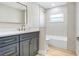 Bright bathroom featuring grey cabinets, gold hardware, a shower and bath combo, and natural light at 40 W Laurel St, Apopka, FL 32703