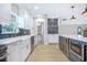Modern kitchen with white cabinets, blue backsplash, stainless steel appliances, and light wood flooring at 40 W Laurel St, Apopka, FL 32703