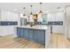 Bright kitchen with white cabinetry, blue backsplash, island, and stainless steel appliances at 40 W Laurel St, Apopka, FL 32703