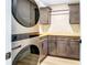 A bright laundry room with grey cabinets, wood countertops, a washer and dryer, and textured stone backsplash at 40 W Laurel St, Apopka, FL 32703