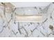 White marble shower featuring gold trim, a shower head, shower faucet, and river stone accent alcove at 40 W Laurel St, Apopka, FL 32703