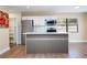 Bright kitchen boasts white cabinets, stainless steel appliances, a functional island, and wood-look flooring at 4015 Kirkland Blvd, Orlando, FL 32811