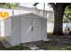 Backyard storage shed with double doors, concrete pavers, and mature tree at 4015 Kirkland Blvd, Orlando, FL 32811