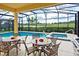 Screened-in patio with outdoor kitchen, dining tables and chairs overlooking a beautiful lake view at 4405 Acorn Ct, Davenport, FL 33837
