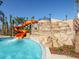 Community pool with orange water slide feature with waterfall and palm trees at 4405 Acorn Ct, Davenport, FL 33837