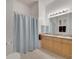 Bathroom features a double sink vanity with tile flooring and shower with a blue curtain at 724 Terrace Ridge Cir # 724, Davenport, FL 33896