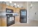 Kitchen featuring black appliances, wooden cabinets, tile floors and adjacent entry door at 724 Terrace Ridge Cir # 724, Davenport, FL 33896