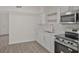 Well-lit kitchen features white cabinets, stainless steel appliances, and light wood-look flooring at 819 Edgewater Dr, Eustis, FL 32726