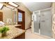 Well-lit bathroom featuring a granite countertop, wood cabinets, and walk-in shower with glass doors at 1039 Whispering Cv, Casselberry, FL 32707