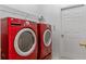Laundry room equipped with red washer and dryer units and storage racks for optimal organization at 11705 Binfield Ct, Orlando, FL 32837
