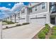 A row of neutral gray two-story townhomes, each with a private two-car garage and manicured landscaping at 12079 Scrub Palm Ln, Orlando, FL 32824