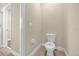 A bright half bathroom with white toilet and sink and door that leads to full bathroom at 14517 Black Lake Preserve St, Winter Garden, FL 34787