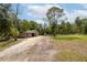 A rustic barn and metal shop building are set on a large lot with mature trees and a long driveway at 1526 Maytown Rd, Oak Hill, FL 32759