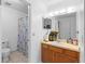 Bright bathroom featuring neutral tiles, wooden vanity, a mirror and shower with blue patterned curtain at 2808 Revere Ct, Casselberry, FL 32707