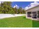 Fenced backyard view featuring lush green grass, trees, and a screened-in patio at 2924 Jebidiah Loop, St Cloud, FL 34772