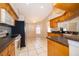 Kitchen featuring tile flooring, wood cabinetry, black countertops, and stainless steel appliances overlooking a breakfast nook at 2924 Jebidiah Loop, St Cloud, FL 34772