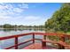 Red wooden dock on a calm lake with a built-in bench and view of trees along the shoreline at 3001 Little Cypress Cv, Winter Park, FL 32792