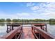 Red wooden dock overlooking a calm lake with trees in the distance under a partly cloudy sky at 3001 Little Cypress Cv, Winter Park, FL 32792