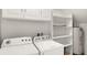 Laundry room with white cabinets, washer, dryer and shelving at 3064 Yellow Lantana Ln, Kissimmee, FL 34747