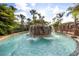 A lagoon style pool with a rock waterfall feature surrounded by tropical landscaping and blue skies at 3118 Magic Kingdom Ct, Kissimmee, FL 34746