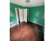 This is a bedroom with green walls, two doors and damaged hardwood floors at 31647 Mount Plymouth Loop, Sorrento, FL 32776