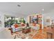 Cozy living room with large windows, white sofas, a built-in display cabinet, and views of the beautifully landscaped backyard at 3332 Stonewood Ct, Orlando, FL 32806