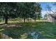 Large, private backyard with lush green grass, mature trees, and a view of the lake and screened lanai at 4012 King Edward Dr, Orlando, FL 32826