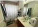 Bathroom featuring a shower with stylish curtain, neutral tiling, and an efficient storage shelf for toiletries at 4012 King Edward Dr, Orlando, FL 32826