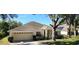 Charming single-story home with attached garage, well-manicured landscaping, and mature trees at 697 Winding Lake Dr, Clermont, FL 34711