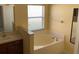 Main bathroom with a soaking tub, a vanity, and a window at 697 Winding Lake Dr, Clermont, FL 34711