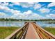 Lake view showing a private wooden dock, calm water, and a beautiful sky filled with fluffy white clouds at 8316 Granada Blvd, Orlando, FL 32836