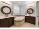 Elegant bathroom featuring a soaking tub, double vanities, and decorative mirrors in a well-lit space at 10072 Hampshire Oaks Dr, Orlando, FL 32825