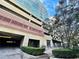 View of the building's parking garage, pedestrian entrance, and surrounding trees at 101 S Eola Dr # 720, Orlando, FL 32801